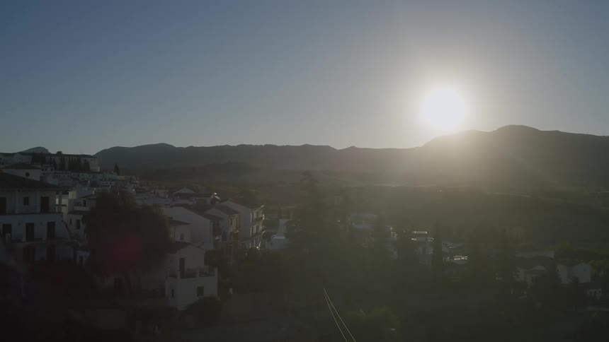 Panorama of houses in an urban city with a mountain range on the horizon and the sun