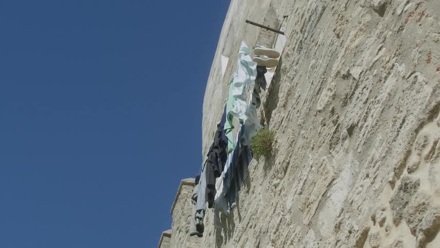 A clothesline in a window that is on a high and rough wall