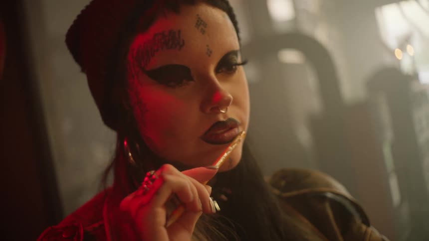 Woman wearing heavy makeup plays with pencil while thinking
