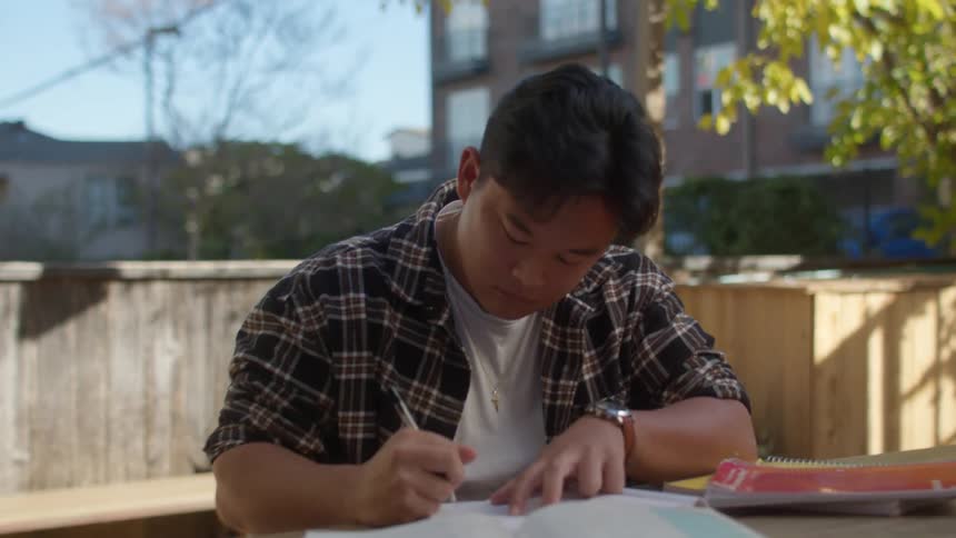 Young man doing homework in the backyard