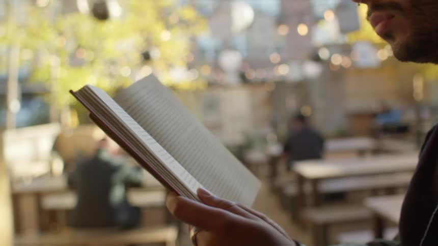 A man is sitting outside reading a book