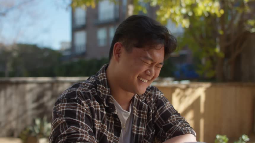 A young man is sitting and looking forward laughing