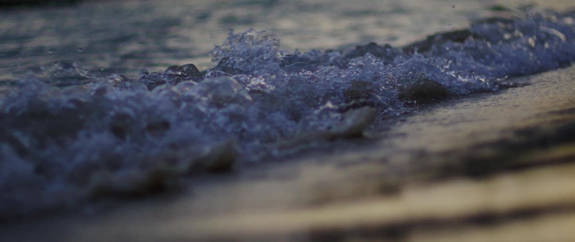 Waves curl and splash as they roll into shore and over the beach