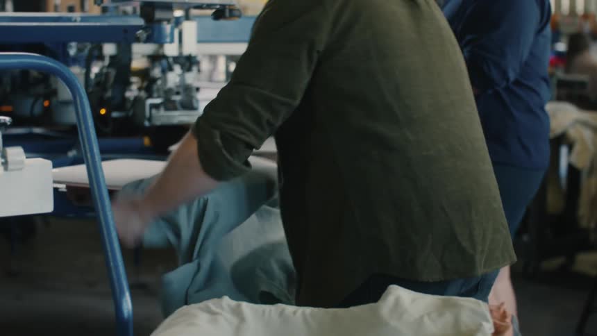 Man placing a plain gray tshirt into a machine