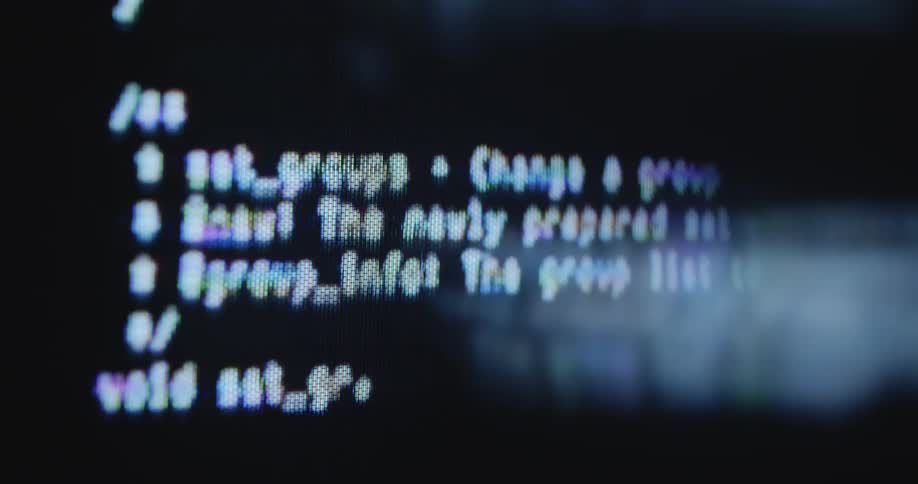Dynamic hand-held macro shot of a computer programming code in java script or HTML that scrolls and moves on the screen while loading or being programmed by a software developer or tech company