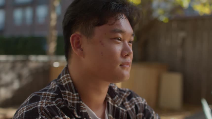 Young man sitting in the backyard listening and nodding