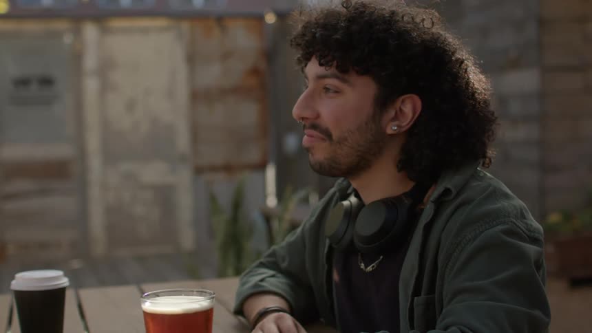 Two men are sitting and talking and on the table there are some drinks
