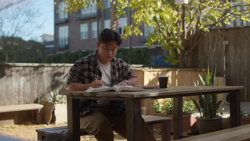 Young man doing homework in the backyard