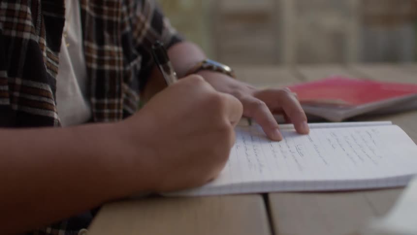 Young man doing homework in the backyard