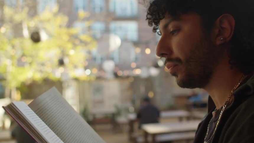 A man is sitting outside reading a book