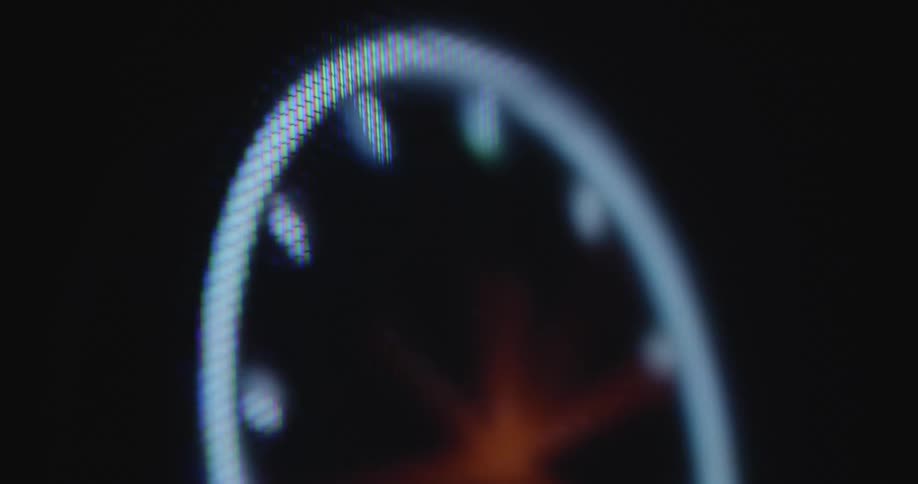 A digital watch with several clock hands spins fast or rapidly on a pixelated computer screen or display causing stress hectic and panic that time is passing and running out