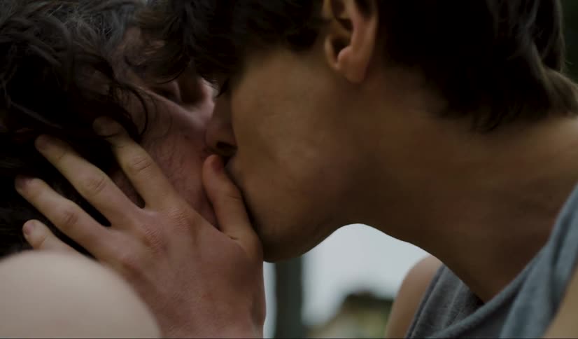 Two men are kissing outside