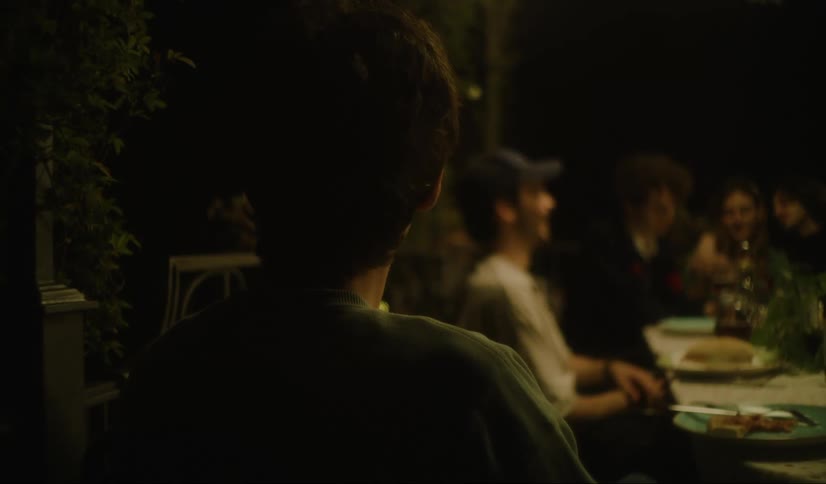 A person has their back to a group of people who are gathered at a table