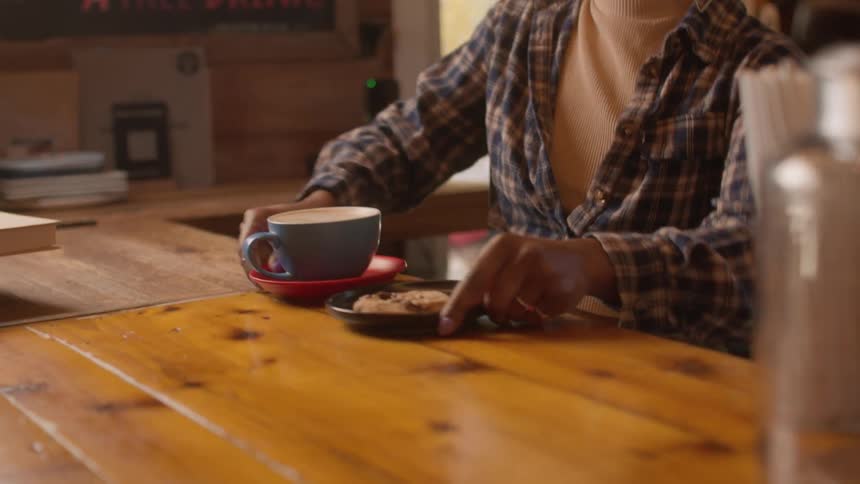 A person serves coffee and a cookie