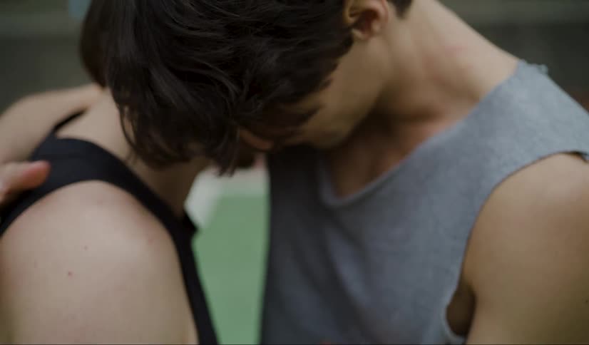 Man comforts friend with a hug as they stand on outdoor court
