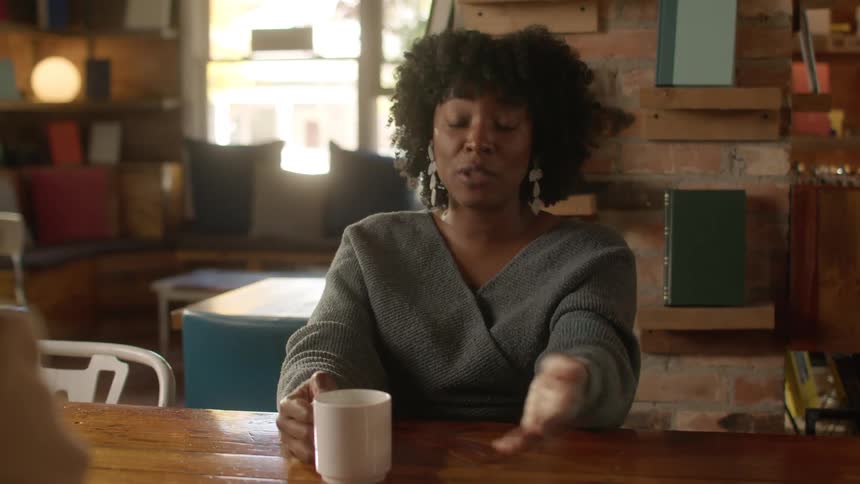 Woman talks to a friend while drinking coffee