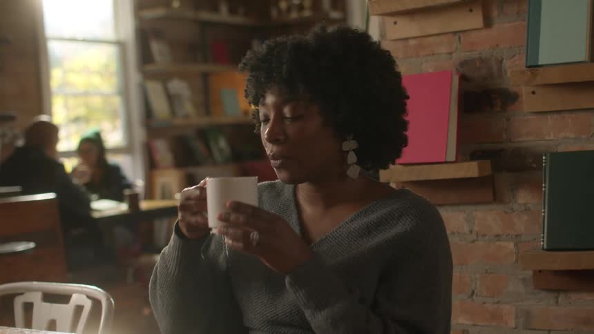 Woman listens to a friends while drinking coffee