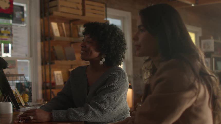 Two women stand and place an order at a coffee shop that sells books