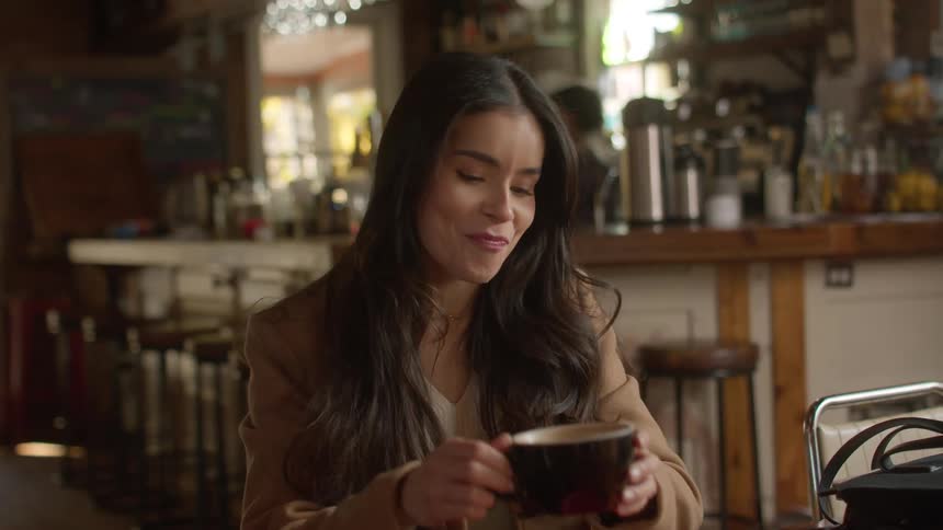 A woman drinks coffee and talks