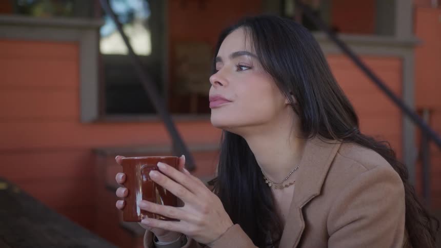A woman is sitting outside with a coffee cup