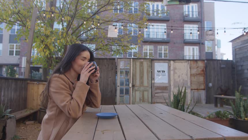 A woman is drinking coffee outside