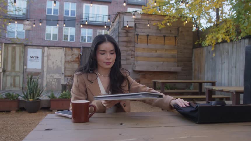 A woman takes folders out of her bag in the restaurant outdoor area