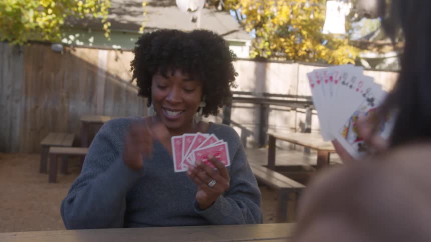 Two friends play cards outside together