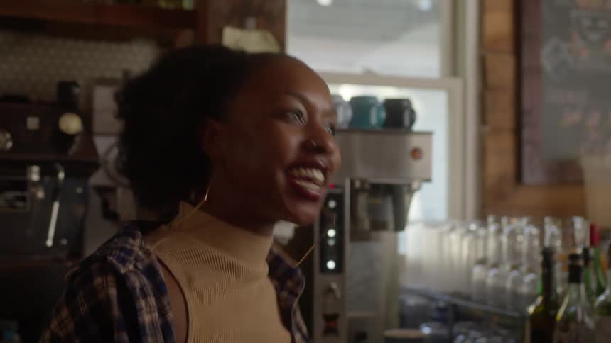 Young happy bartender talks to customers