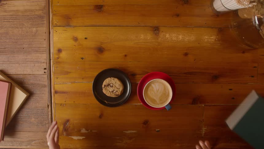 Men share books and pastries at large wooden table