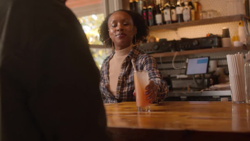 Bartender serves a drink to a customer