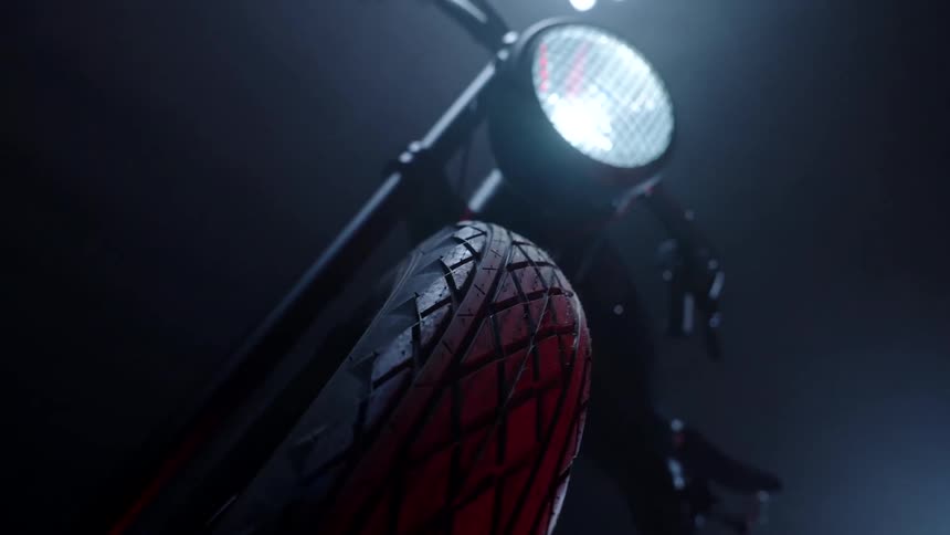 Frontal view of a motorcycle with the headlight on inside a dark room