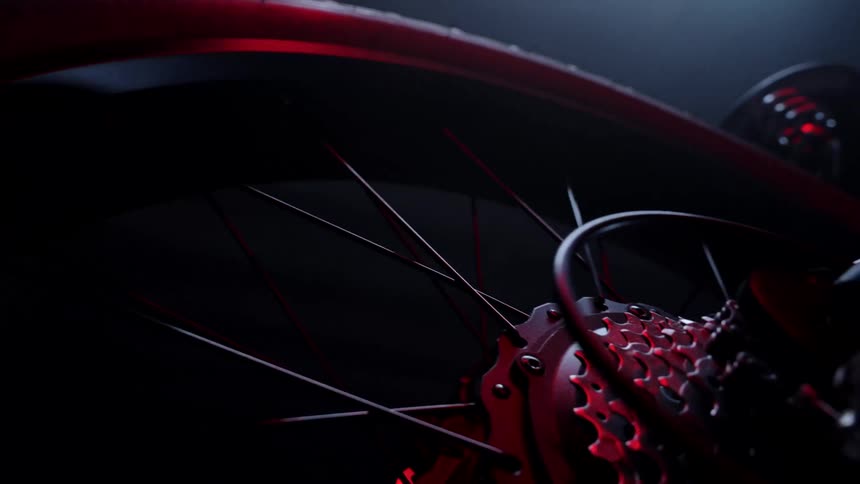 A bicycle has multiple gears on its wheel as a light shines upon it