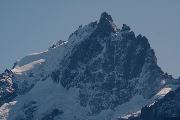 A huge stone mountain with snow on its surface