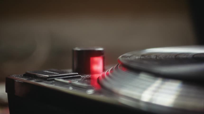 Close up of a finger pressing a button on a record player