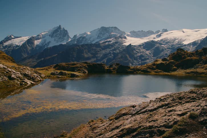 A small lake on a rocky mountain during the day