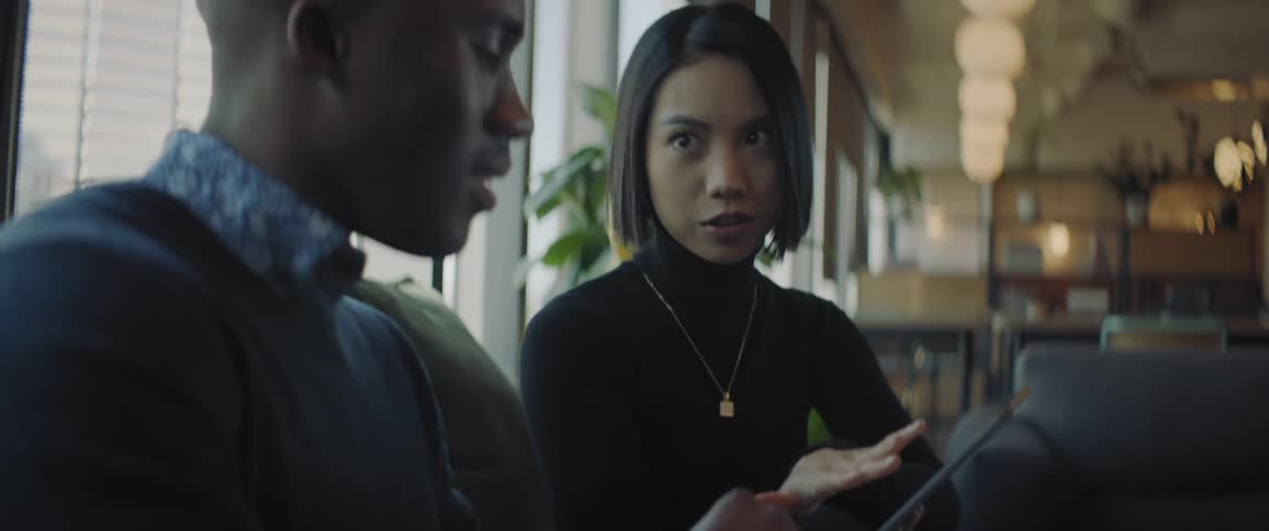 Two coworkers talk while looking at a tablet