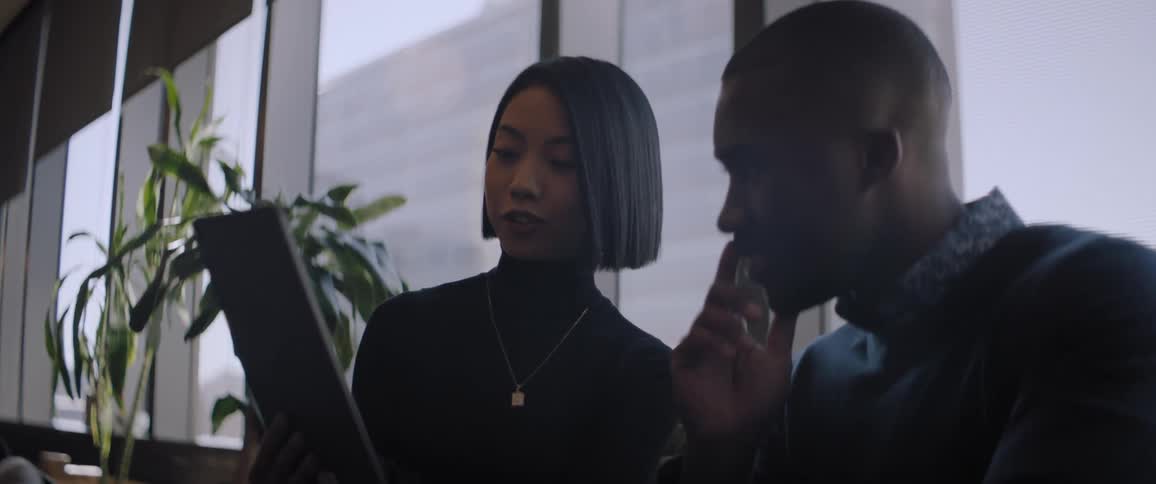 A woman and a man are talking while looking at a tablet