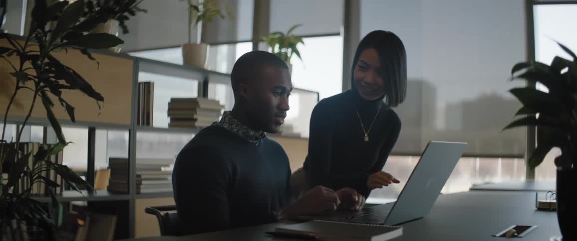 A man and a woman in an office working on a computer
