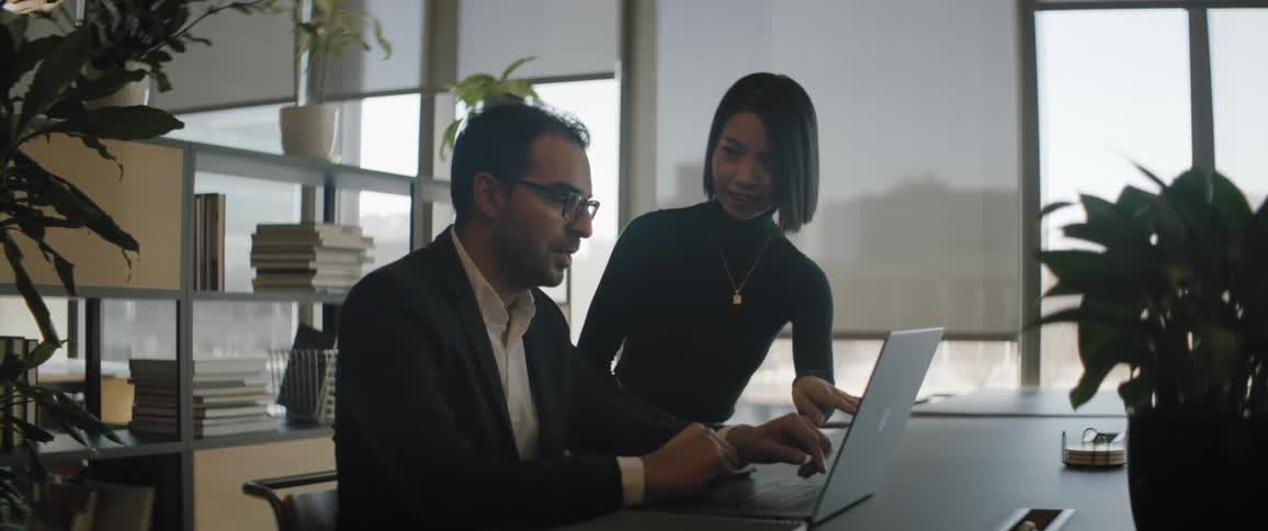 Two office workers high five while reading the laptop