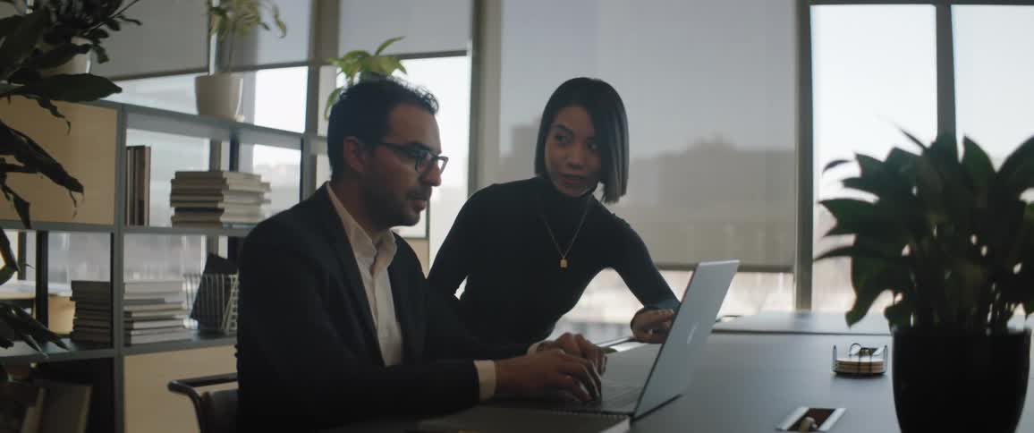 Two people in the office look at a laptop together