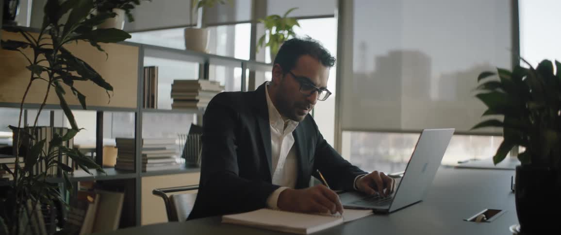 A man writing and working on his pc in the office