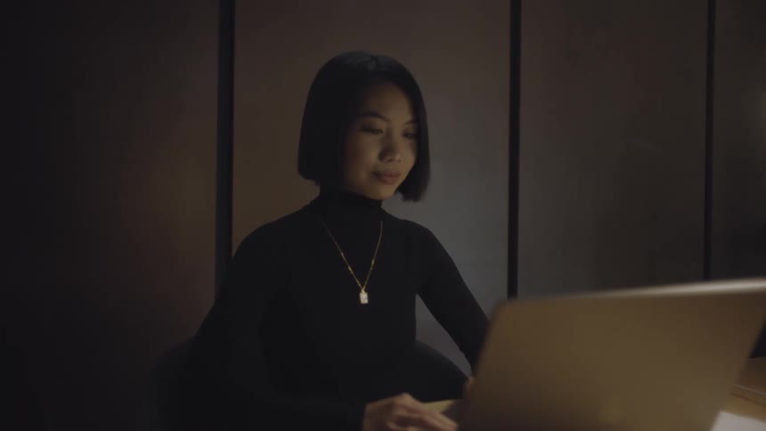 Lady typing on a laptop while seated inside an office