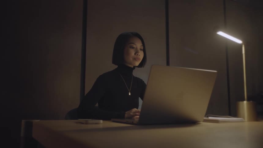 A lady putting on a black cloth and is working on her laptop