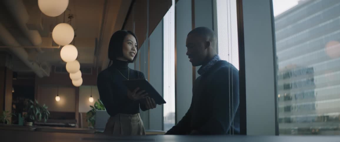 A woman is showing a man her tablet in the office