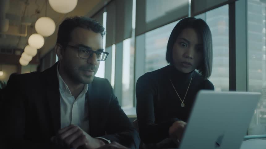 Coworkers talk while looking at a laptop