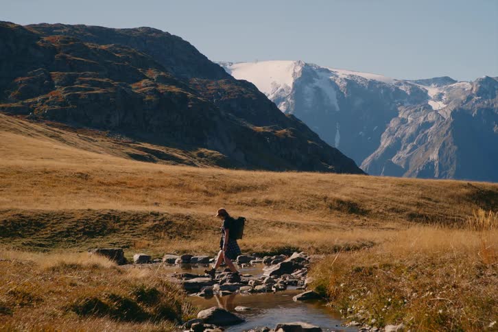 A young girl crossing a stream on a hill in nature
