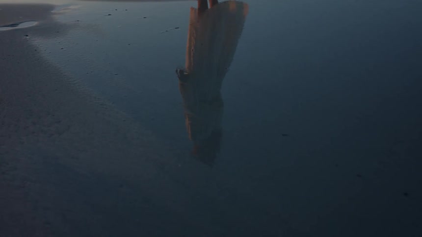 Reflection of a person reflecting on the beach during sunset
