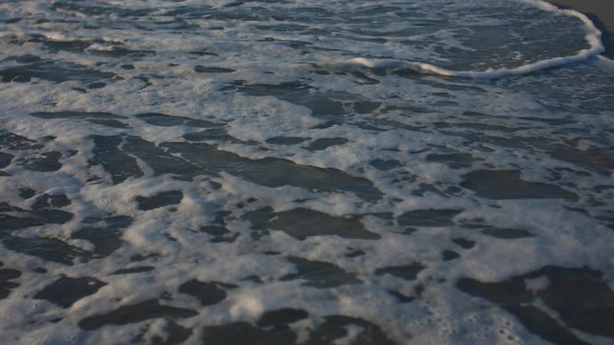 Waves with foam breaking on the beach in the morning