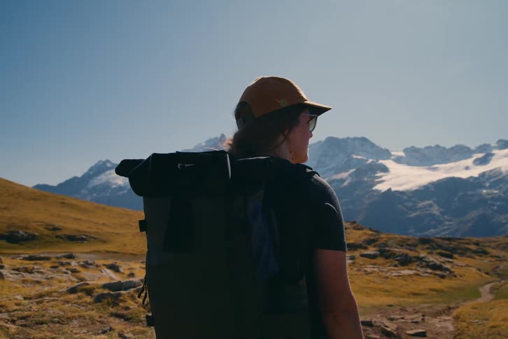 A woman on a hill admiring the snowy mountain landscape