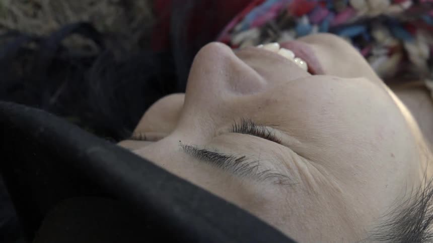 Extreme close up of a smiling woman lying outdoors on a bright summer afternoon.